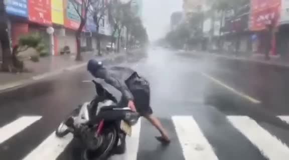 Nam thanh niên gồng mình, cố dắt xe vào lề đường trong gió bão