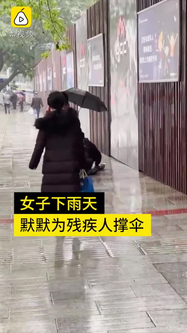 Người phụ nữ cầm ô che cho người khuyết tật bò trên đường