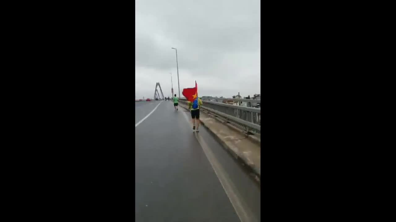 Cổ động viên chạy bộ cầm cờ đi đón đội tuyển U23 Việt Nam
